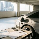 16:10 비율, 한국 도심 주차장에 주차된 전기차와 자동차 계약서, 계산기, 세금 안내 서류가 함께 놓인 장면, 전기차 취득세 감면과 세제 혜택을 상징하는 이미지, 깔끔하고 현실적인 사진 스타일, 여백이 충분한 구성